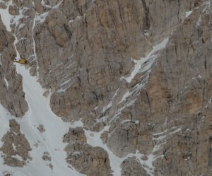 elicottero in avvicinamento a alpinista che sta segnalando con le braccia aperte - bordo foto