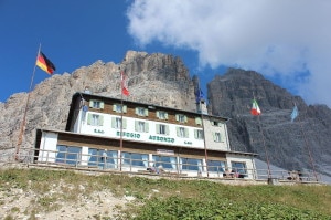 Il rifugio Auronzo e, alle sue spalle, la Ovest e la Grande delle Tre Cime di Lavaredo (Photo courtesy of commons.wikimedia.org)