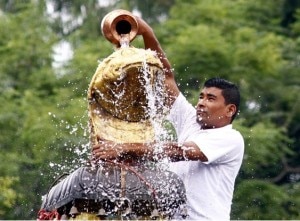 In this file photo a devotee offer Jal (water) before offering milk, flower, fruits, incenses and other religious items on the day of Nag Panchami at Nagpokhari in Kathmandu.  