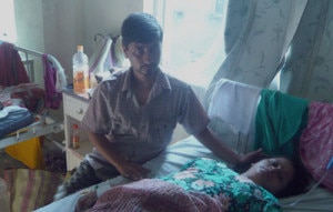 Ghanashyam Bhattarai, father of the quadruplets sits by his wife Deepa at the hospital where Deepa gave birth to the babies. Photo: Courtesy to onlinekhabar 