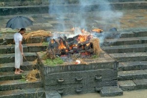 In this file photo, a priest watches a funeral pyre at a cremation in Nepal.