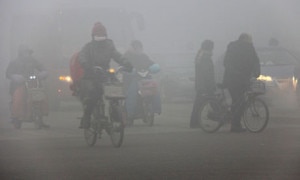 Chinese cycle through smog and pollution over Beijing's road. Photo: Agency