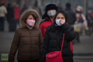 In this file photo by AFP, pedestrians wearing masks wait to cross a road during severe pollution in Beijing on January 12, 2013. 