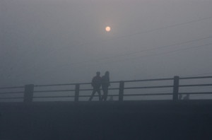 Two men walk along the bride on a foggy morning in Kathmandu as the Sun shines low in the backdrop. Photo: File photo/NMF