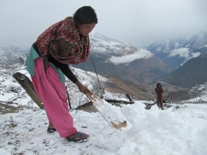 A woman clears snow from the rooftop in Mathitum village in mountainous Mugu district on Saturday. Photo: ekantipur.com