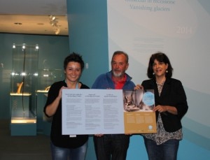 Angelika Fleckinger, direttrice del Museo Archeologico dell'Alto Adige, Gottfried Leitgeb, gestore del rifugio Vedrette di Ries e scopritore di reperti archeologici sui ghiacciai, e Catrin Marzoli direttrice dell'Ufficio provinciale Beni archeologici mostrano il cartello che è appeso sui rifgui alpini altoatesini. (Photo courtesy of Museo Archeologico dell’Alto Adige/Ripartizione Musei Provincia di Bolzano)