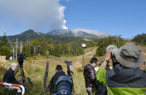 Photographers gather at the foot of the Mount Ontake in Nagano prefecture on September 28, 2014. The volcano erupted in central Japan on September 27, shooting ash and rocks into the air that reportedly left eight hikers injured and forced 150 people to shelter in cabins near the summit. The eruption of the 3,067-metre (10,121-foot) Mount Ontake happened around midday, the meteorological agency said. Image courtesy to AFP.