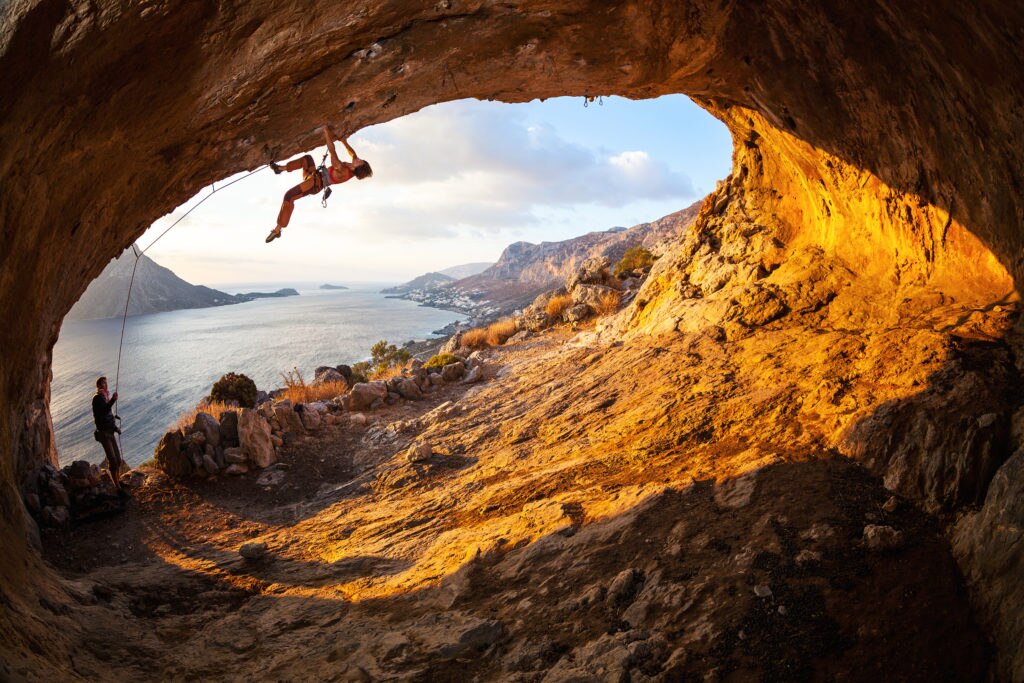 Young woman lead climbing in cave with beautiful view in background ; Shutterstock ID 243818704