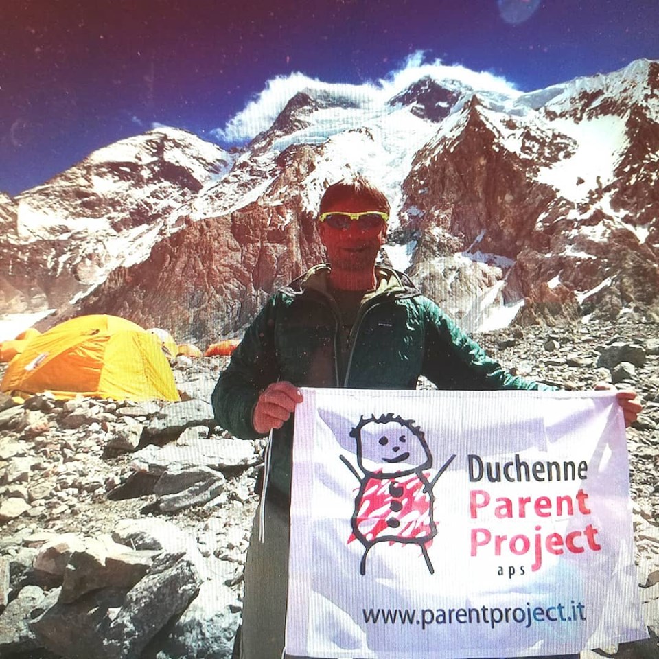 Mario Vielmo al campo base del Broad peak con la bandiera del Parent Project - Foto FB @Mario Vielmo