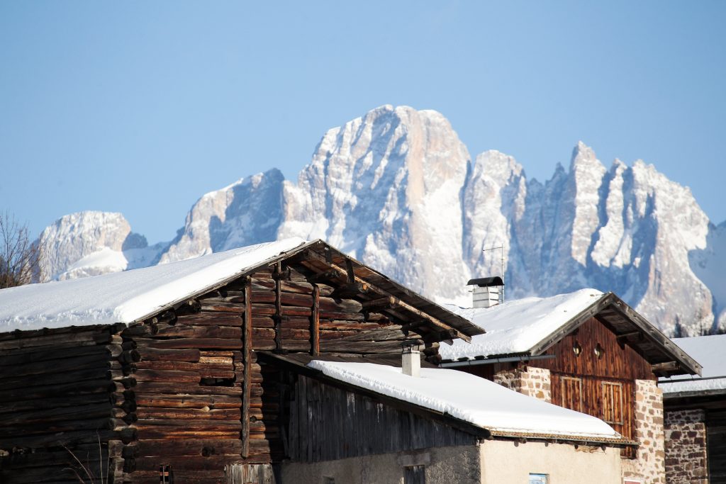 una tipica baita nel paese di Bellamonte; sullo sfondo, le Pale di San Martino. Foto F. Modica