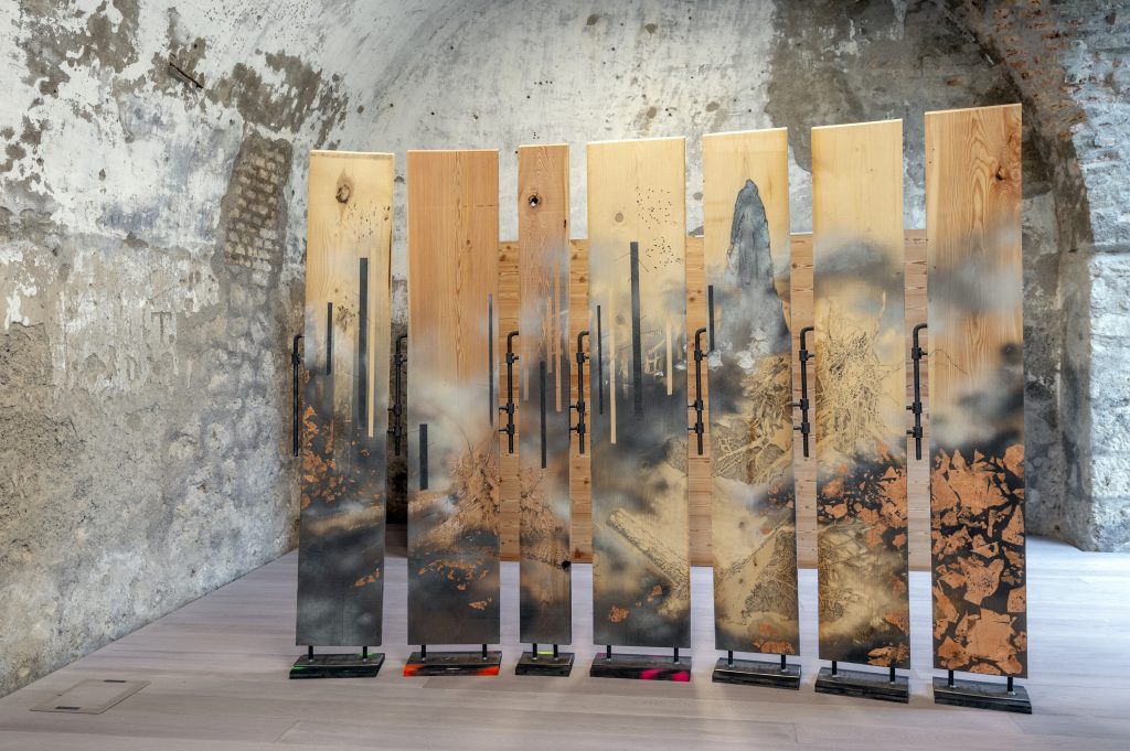 Dimitri Giannina, PARA el VIEN to, 2019, quattro breghe di abete rosso, quattro di larice, cardini, spray, olio, matita, grafite, foglia d’oro, pallini in acciaio (rosata), incisione. Opera inclusa nella mostra “Altri Dardi”, Forte di Monte Ricco, a cura di G. D’Incà Levis, estate 2019. Foto: Giacomo De Donà
