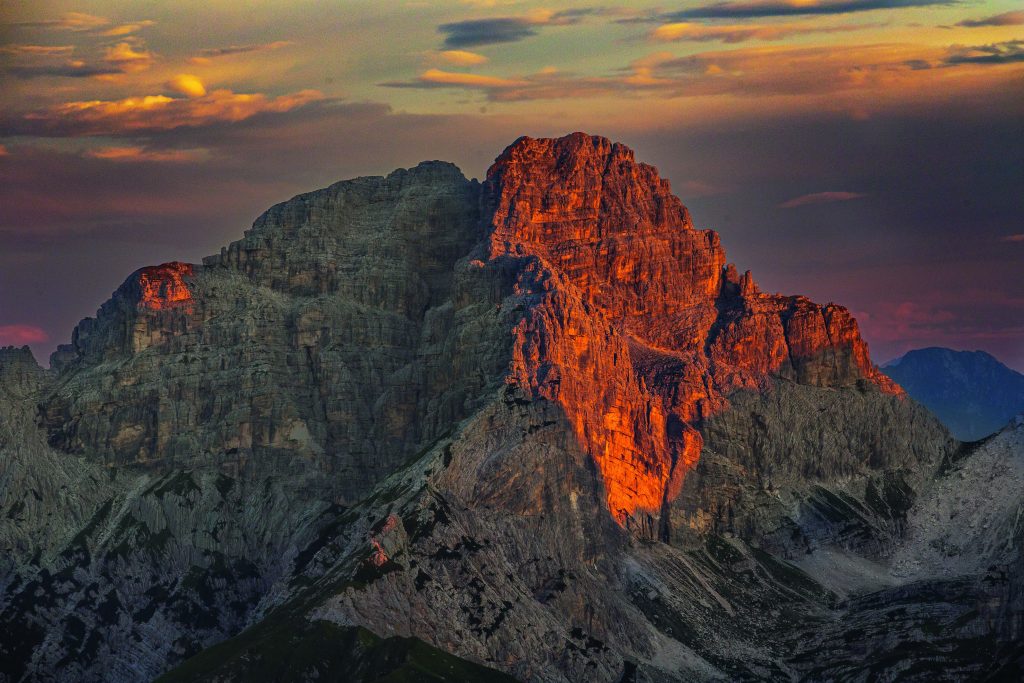  Dalla cima del Pizzocco (2186 m), le prime luci del giorno illuminano il Sass de Mura (2547 m), nel Gruppo del Cimonega. Foto @ Tommaso Forin