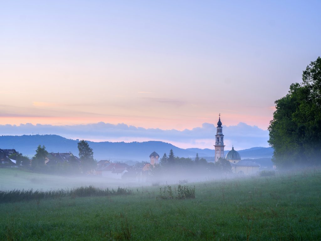 Bruma all'alba verso il centro storico di Asiago col Duomo di San Matteo e la torre campanaria del Palazzo Municipale