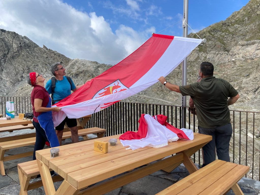 Il presidente Kompatscher mentre issa la bandiera della Provincia insieme ai gestori del rifugio Petrarca (Foto: Provincia di Bolzano/ASP/G.News)