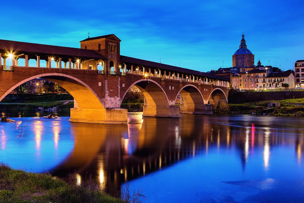 Pavia. Simbolo della città, il Ponte Coperto attraversa il Ticino collegando il centro storico al quartiere di Borgo Ticino, un tempo abitato dalle lavandaie. La struttura attuale è una copia dell’antico ponte del XIV secolo, danneggiato dai bombardamenti delle forze alleate nel 1944. Foto Maurizio/Adobe Stock