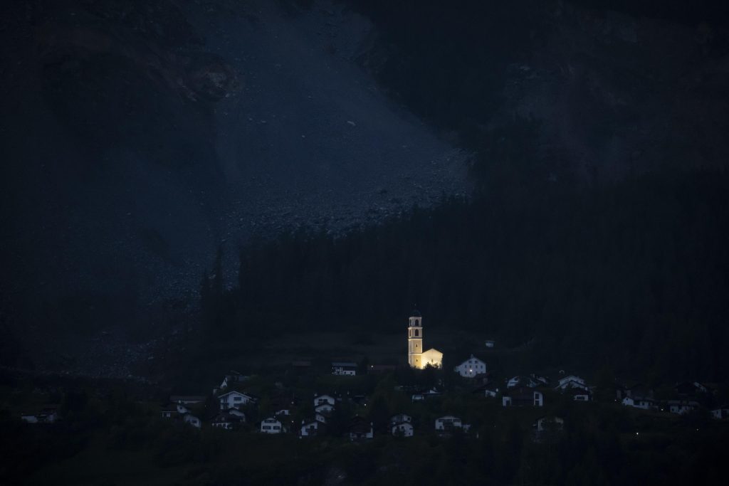 La chiesa di Brienz illuminata circondata dal buio del villaggio evacuato, 12 maggio 2023. Foto ANSA EPA/GIAN EHRENZELLER