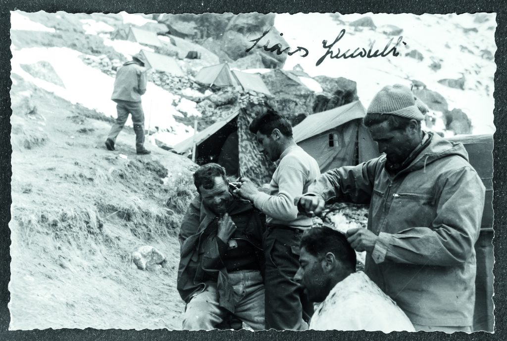 Walter Bonatti (in secondo piano) taglia i capelli a Lacedelli al Campo base del K2. | foto arch. Alberta Lacedelli