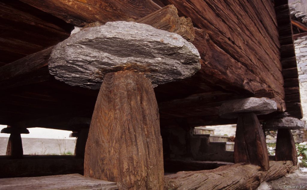 Il tipico “fungo Walser, su cui poggiano le case, consentendo l’aerazione e la circolazione dell’aria che rende meno umida l’abitazione. Anche i particolari sono importanti per descrivere l’architettura tipica delle case alpine. Nikon F90x; Nikkor 35-70 2,8 AFD; Fujichrome Velvia.