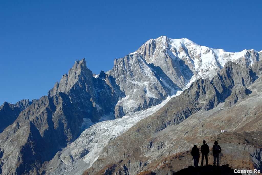 La Silhouette, un modo di rappresentare gli escursionisti, durante un trekking ( https://www.montagna.tv/219787/corredo-fotografico-per-il-foto-trekking/ ). Il Monte Bianco è sullo sfondo. La silhouette, ovvero la sagoma di una persona nera e priva di dettagli, con lo sfondo di una cima è un modo classico per rappresentare questo tipo di fotografia, considerando anche che la mancanza di colore dell’escursionista non distrae l’occhio dell’osservatore dalla scena generale. Tecnicamente si misura la parte più luminosa dell’immagine, per esempio il cielo, e poi si sottoespone in modo da rendere la persona, che si trova già in una zona di ombra netta, priva di dettaglio, insomma totalmente nera. La Silhouette è anche un modi interessante di rappresentare l’elemento umano nel paesaggio ( https://www.montagna.tv/221679/lelemento-umano-nella-fotografia-di-paesaggio/ ). Nikon D 300; Nikkor 24-120 AFG 3,5 / 4,5; f 11; 1/50; iso 200. Sottoesposizione di 1 stop. Misurazione spot sulle rocce grigie del Monte Bianco.