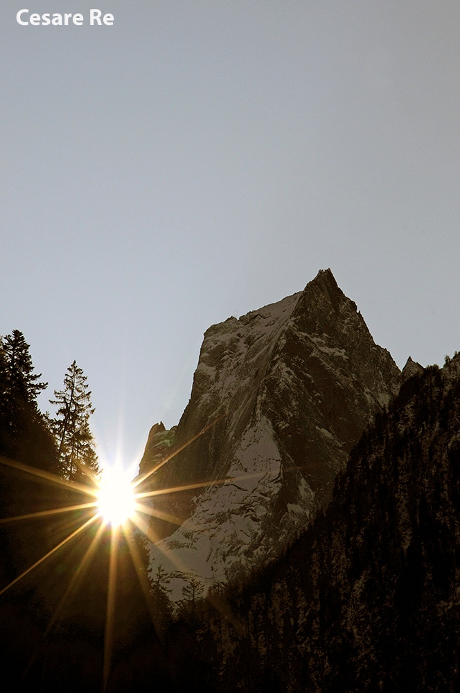 Lo spettacolo del Pizzo Badile, con il sole che spunta dallo spartiacque. Attimi brevi, effimeri, prima che il sole si alzi ulteriormente. Da notare che i raggi sono molto più evidenti in basso, dove incontrano la superficie delle rocce e degli alberi.  L’immagine è nata quasi per caso, verso la fine dell’autunno. Ero di passaggio per andare in Engadina, per scattare immagini per un libro sul Bernina e sul Badile. Appena entrato in Val Bregaglia, nei pressi di Promontogno, ho visto un fascio di luce, proprio ai piedi della cresta del Badile. Intuendo il prossimo sorgere del sole, ho piazzato il treppiede e regolato l’80-200. Appena il tempo di scattare qualche immagine e il sole è scomparso dietro i larici. Di tutte le immagini ottenute nei giorni successivi, questa rimane una delle più interessanti e peculiari. Nikon D700; Nikkor 80-200 2,8 AFD; f 16; 1/60; ISO 200 