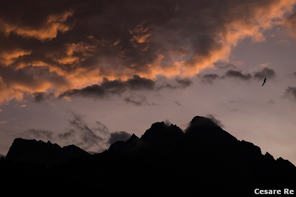 Cima Colbricon, nel gruppo dei Lagorai, in effetto silhouette, con un cielo al tramonto, coloratissimo e suggestivo. Una foto che si può comporre in diversi modi, anche dando predominanza al cielo. In questo caso, però, l’orizzonte è stato poso quasi a metà, per dare risalto sia alle nuvole, sia alle cime scure, in silhouette. Fujifilm XT 3; 1/500 sec; f/8; ISO 200. Misurazione in spot sul cielo. Silhouette accentuata sia in ripresa, con sottoesposizione, sia in post produzione. 