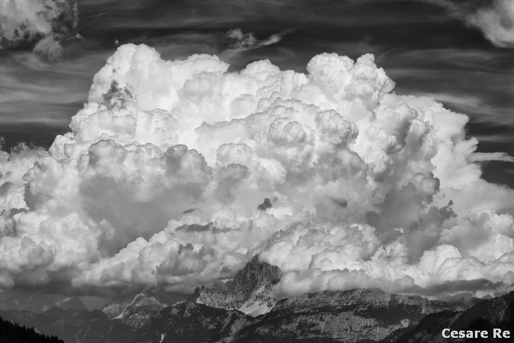 Il Civetta sommerso dalle nubi. Il profilo della montagna è netto e riconoscibile, ma solo per gli esperti. Il gioco con le nuvole è evidente e molto peculiare. Il cielo è predominante e occupa molto nella composizione. Lo scatto è stato convertito in bianco e nero con silver efex pro. Nikon D810; Nikkor 70-200 4 afg, focale 100; 1/160 sec; f 81/400 sec; f/9; ISO 200. Per esaltare le nuvole è stato usato un filtro polarizzatore. 