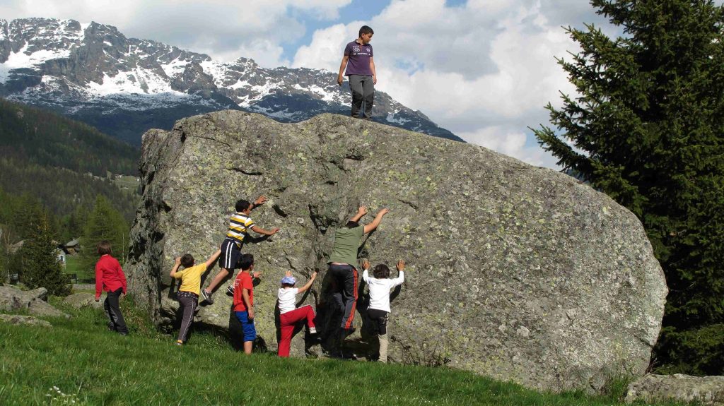 Bimbi alle prese con il gioco arrampicata su un blocco di gneiss in Valmalenco, foto L. Maspes