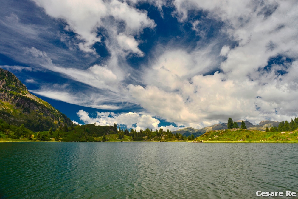 Lago di Colbricon, con nubi spettacolari, piuttosto frequenti, in zona. Nikon D800; Nikkor 18 AIS; 1/100 sec; f 11; iso 100; filtro polarizzatore. Il grandangolare esalta il cielo e la prospettiva, anche perché la fotocamera è posta quasi a livello dell’acqua. Quando ci sono molte nubi e il cielo è azzurro terso, con il sole alle spalle, è il momento perfetto per usare il polarizzatore. 