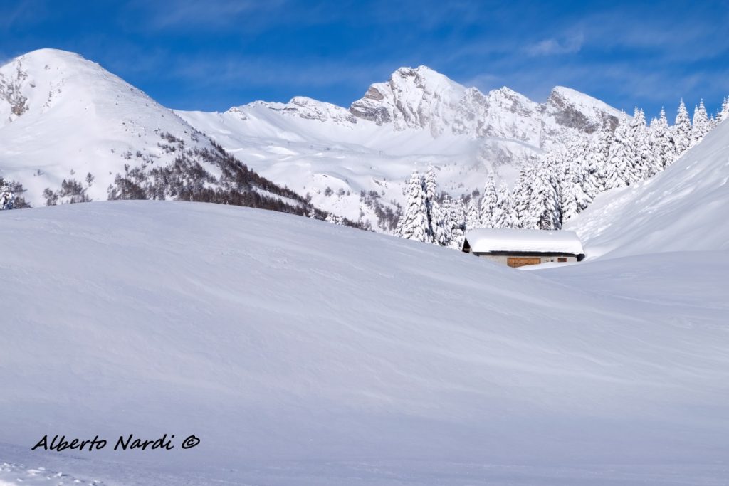 Una stalla isolata lungo il percorso invernale per Furestin. Sullo sfondo le cime delle Alpi dell