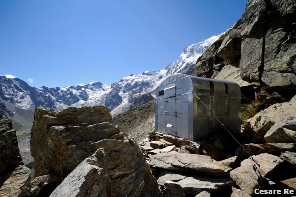 Il Bivacco Valentino Belloni (2509 m), sopra Macugnaga. Sullo sfondo la Punta Gnifetti e la Punta Tre Amici. Foto Cesare Re